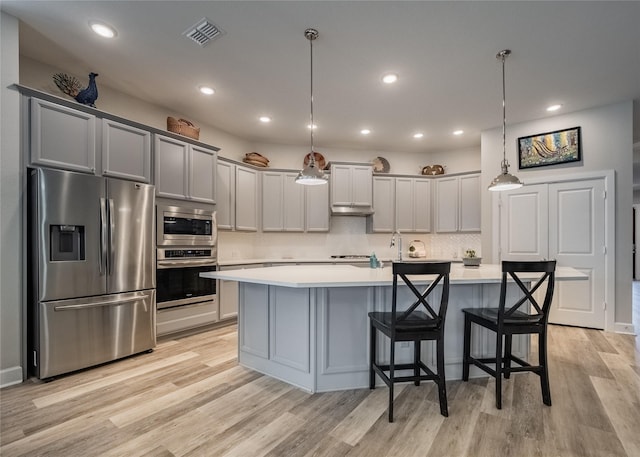 kitchen featuring stainless steel appliances, light wood finished floors, light countertops, and visible vents