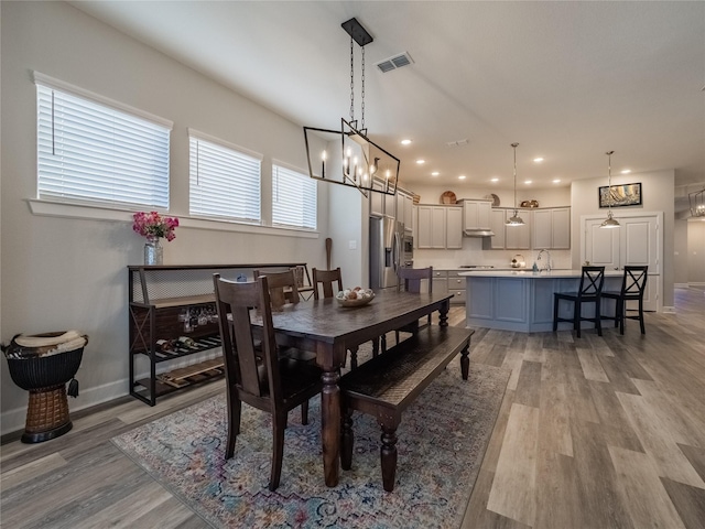 dining area with light wood-style flooring, visible vents, and baseboards