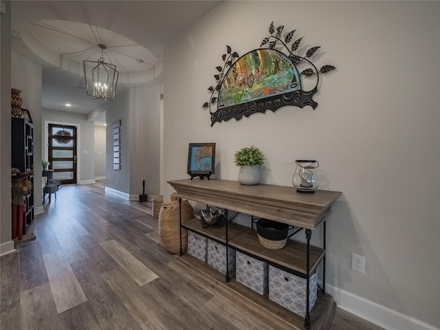 hallway featuring a notable chandelier, baseboards, and wood finished floors