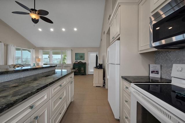 kitchen with dark stone counters, white appliances, white cabinetry, and open floor plan