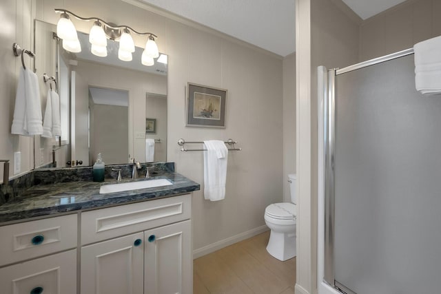 bathroom with a stall shower, baseboards, toilet, wood finished floors, and vanity