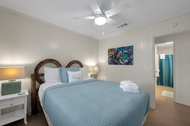 bedroom featuring ceiling fan, ornamental molding, wood finished floors, and visible vents