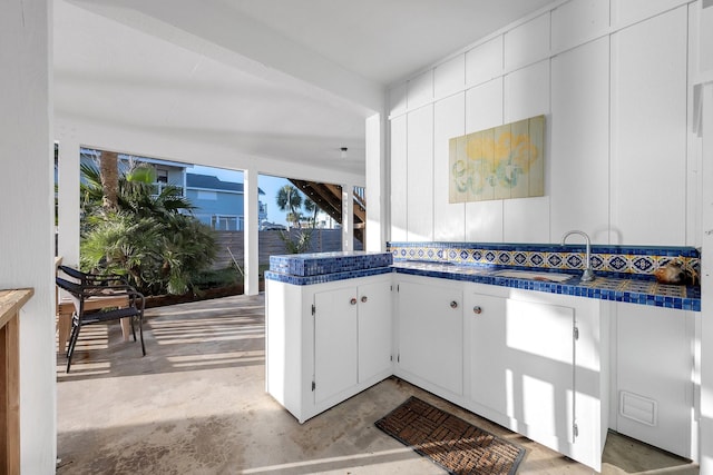 kitchen featuring dark countertops, white cabinets, a sink, and unfinished concrete floors