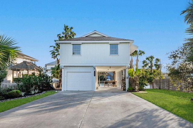 view of front facade featuring driveway, an attached garage, fence, a front lawn, and a carport