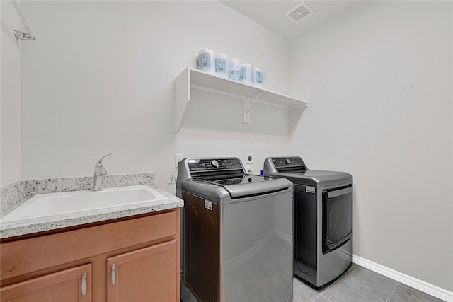 laundry area featuring washer and clothes dryer, light tile patterned floors, cabinet space, visible vents, and a sink