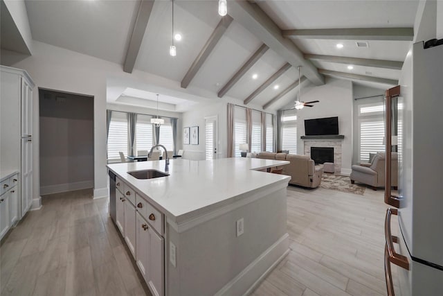 kitchen featuring an island with sink, open floor plan, light countertops, white cabinetry, and a sink