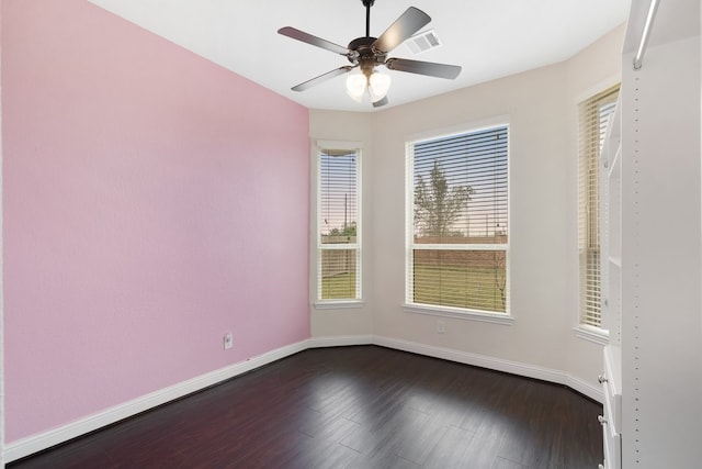 unfurnished room with visible vents, dark wood finished floors, baseboards, and ceiling fan