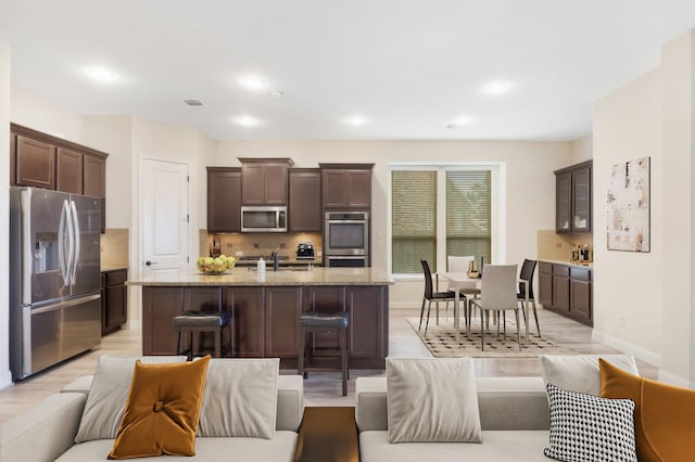 living room featuring recessed lighting, baseboards, visible vents, and light wood finished floors