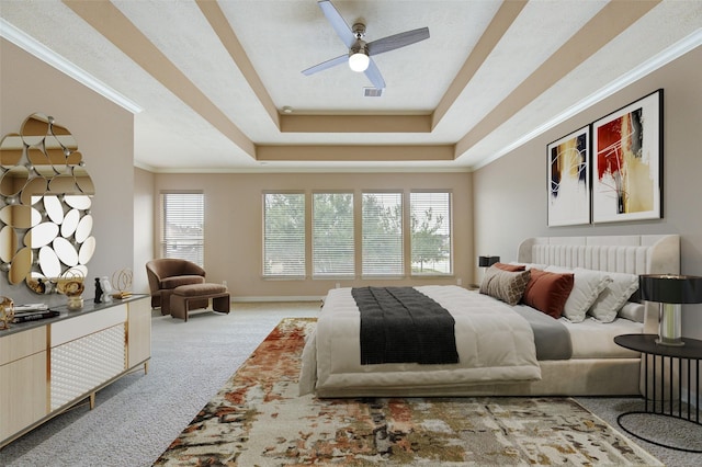 carpeted bedroom featuring baseboards, ornamental molding, a ceiling fan, visible vents, and a raised ceiling