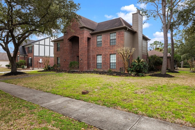 view of front of home featuring brick siding, a chimney, and a front yard