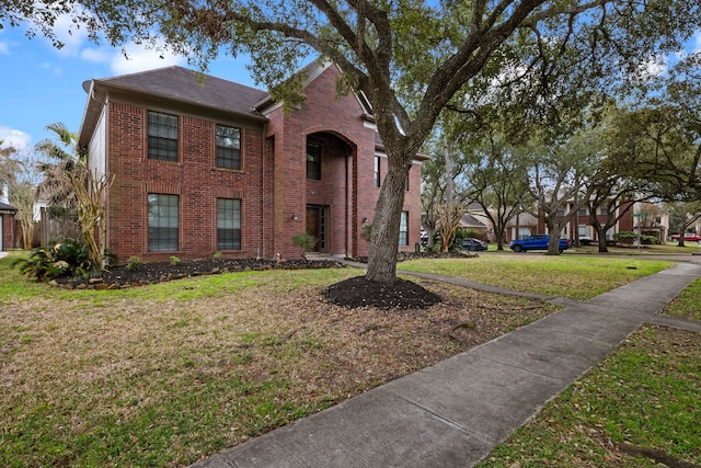 traditional home with brick siding and a front lawn