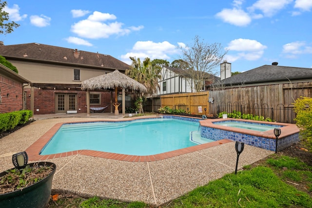 view of swimming pool featuring a fenced backyard, a pool with connected hot tub, and a patio