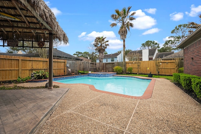 view of pool with a fenced backyard, a pool with connected hot tub, and a patio