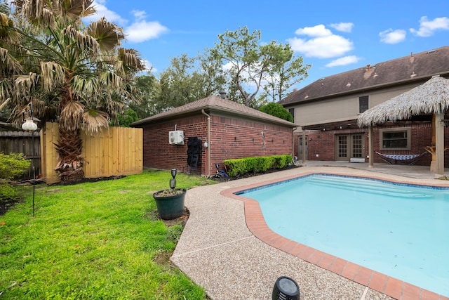 view of pool featuring fence, french doors, a lawn, a fenced in pool, and a patio area