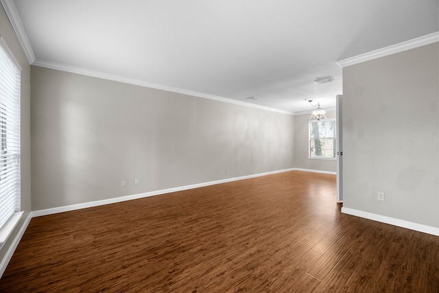 empty room featuring dark wood-style floors, ornamental molding, baseboards, and a notable chandelier