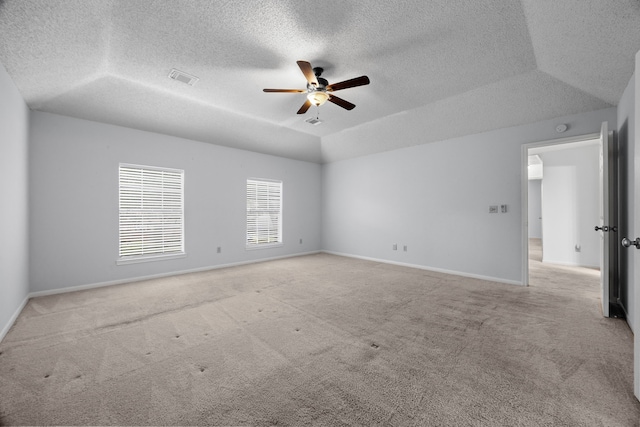 empty room featuring light carpet, vaulted ceiling, visible vents, and a ceiling fan