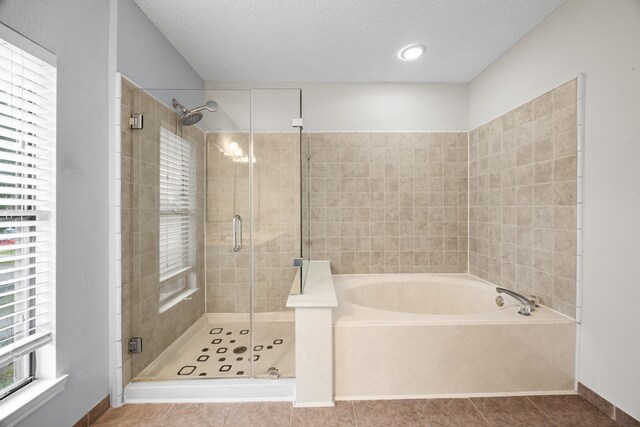 bathroom featuring a stall shower, tile patterned flooring, a garden tub, and a textured ceiling