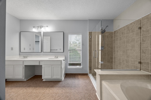 full bath featuring a sink, a shower stall, a textured ceiling, and double vanity