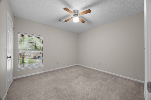 spare room with baseboards, visible vents, a textured ceiling, and light colored carpet