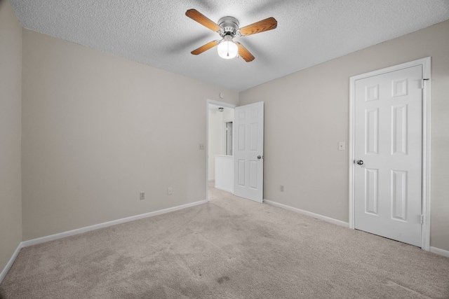 empty room with carpet, baseboards, and a textured ceiling