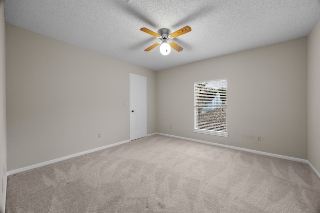 empty room featuring a ceiling fan, light colored carpet, a textured ceiling, and baseboards