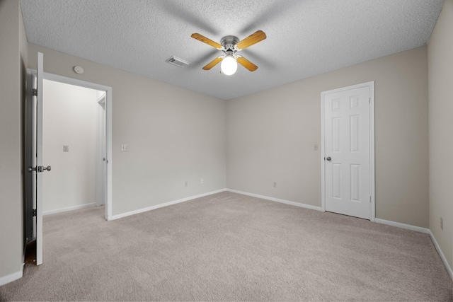 carpeted spare room with baseboards, a textured ceiling, visible vents, and a ceiling fan