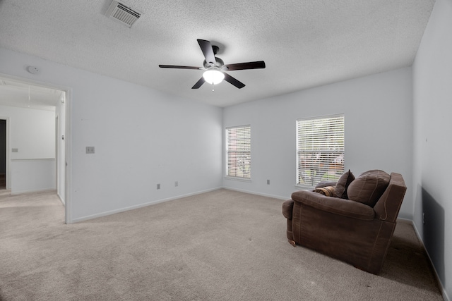 living area featuring attic access, baseboards, visible vents, light colored carpet, and a textured ceiling