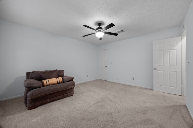 sitting room with a textured ceiling, carpet flooring, visible vents, baseboards, and a ceiling fan