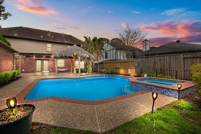 view of swimming pool featuring a patio, a fenced backyard, and a pool with connected hot tub