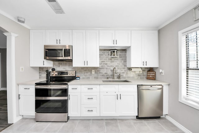 kitchen featuring stainless steel appliances, a sink, visible vents, light countertops, and tasteful backsplash