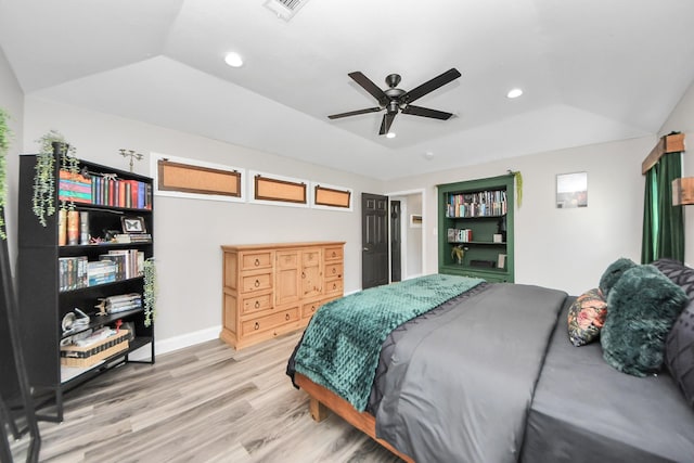 bedroom with light wood-style flooring, recessed lighting, visible vents, vaulted ceiling, and a tray ceiling