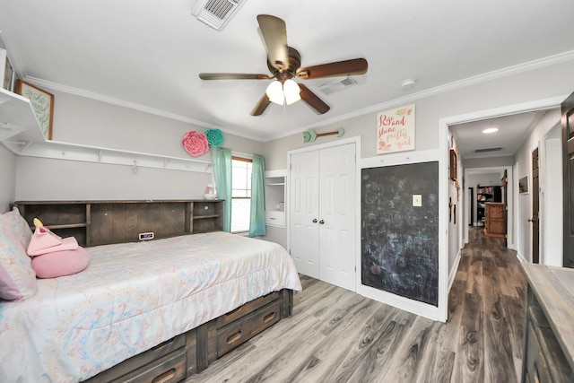 bedroom featuring crown molding, a closet, visible vents, and wood finished floors