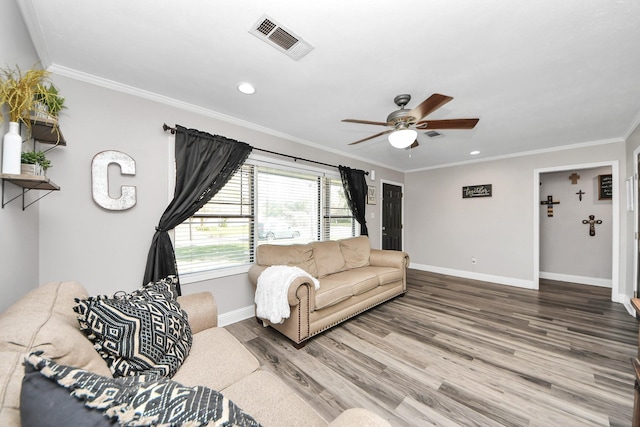 living room with baseboards, wood finished floors, visible vents, and crown molding