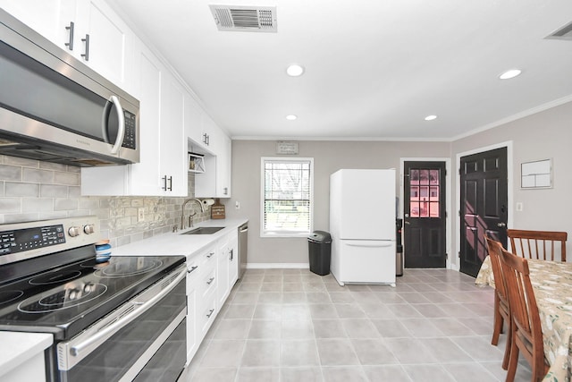 kitchen with stainless steel appliances, a sink, visible vents, light countertops, and backsplash