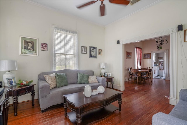 living room with ceiling fan, wood finished floors, visible vents, baseboards, and crown molding