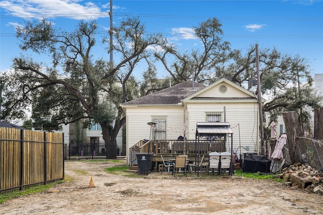 rear view of house featuring a deck and fence