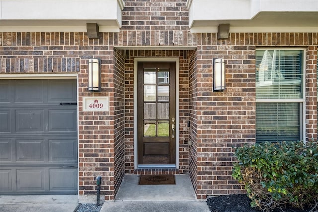 view of exterior entry with a garage and brick siding