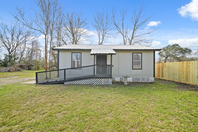 view of front of home with metal roof, fence, and a front lawn