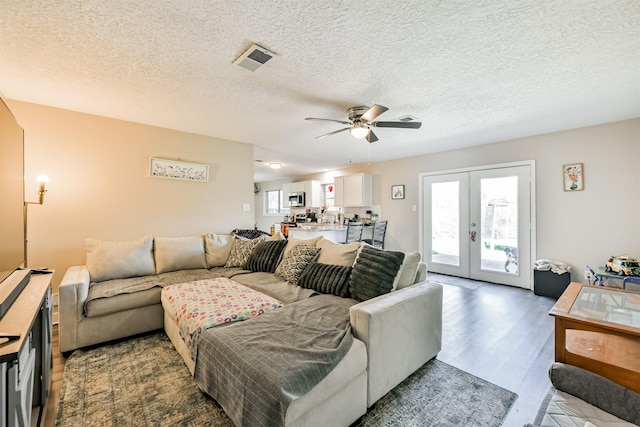 living room featuring visible vents, a ceiling fan, wood finished floors, a textured ceiling, and french doors