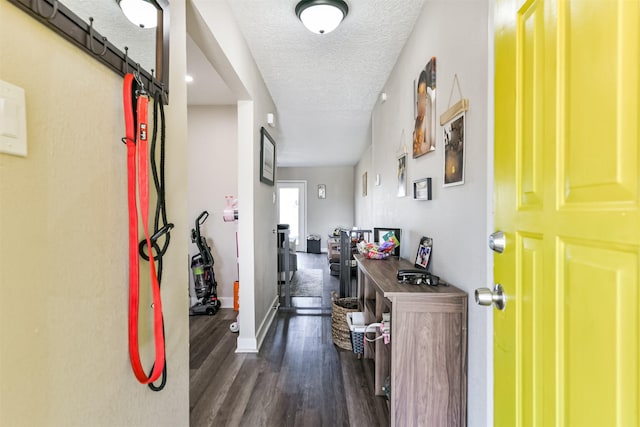 hallway with baseboards, a textured ceiling, and wood finished floors