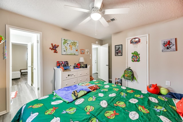 bedroom featuring visible vents, ceiling fan, a textured ceiling, and wood finished floors