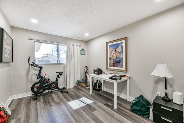 office space with recessed lighting, a textured ceiling, baseboards, and wood finished floors