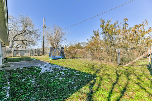 view of yard with a trampoline and a fenced backyard