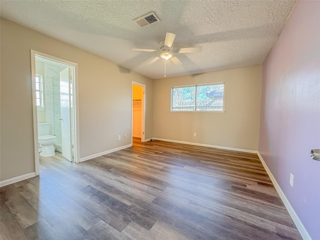 unfurnished bedroom with baseboards, wood finished floors, visible vents, and a walk in closet