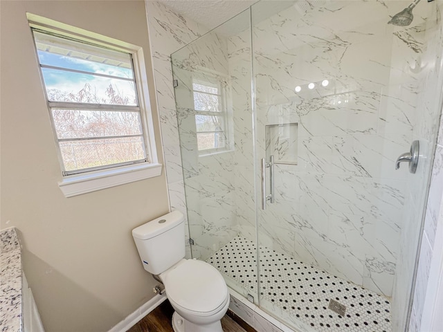 full bathroom with toilet, a marble finish shower, baseboards, and wood finished floors