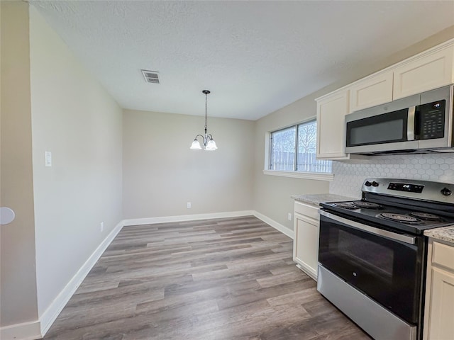 kitchen with light wood finished floors, baseboards, visible vents, and stainless steel appliances