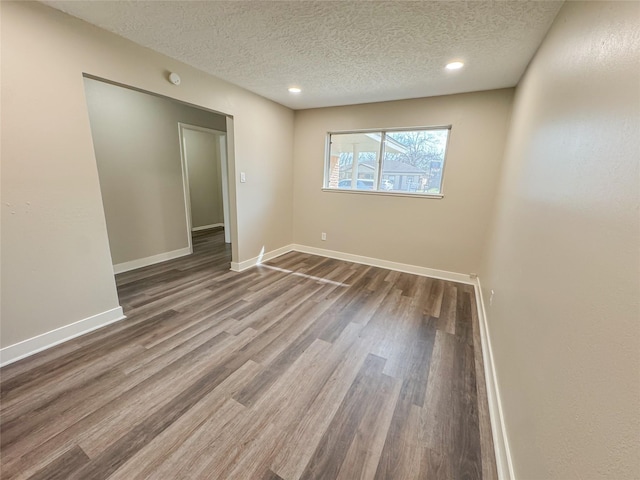 empty room with recessed lighting, a textured ceiling, baseboards, and wood finished floors