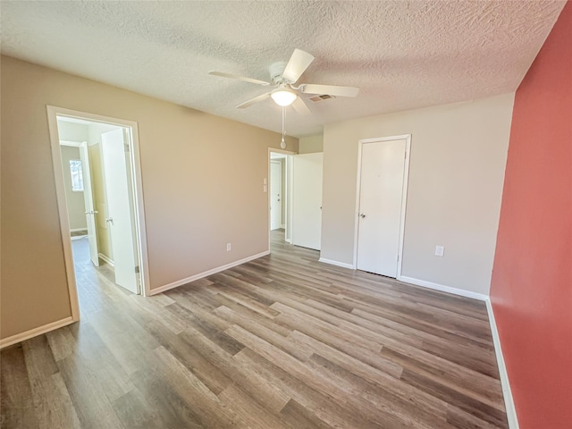 unfurnished bedroom featuring a ceiling fan, baseboards, visible vents, and wood finished floors