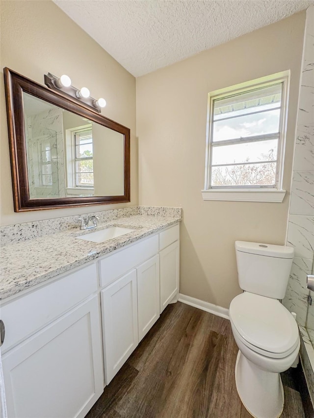 bathroom featuring toilet, a textured ceiling, a wealth of natural light, and wood finished floors