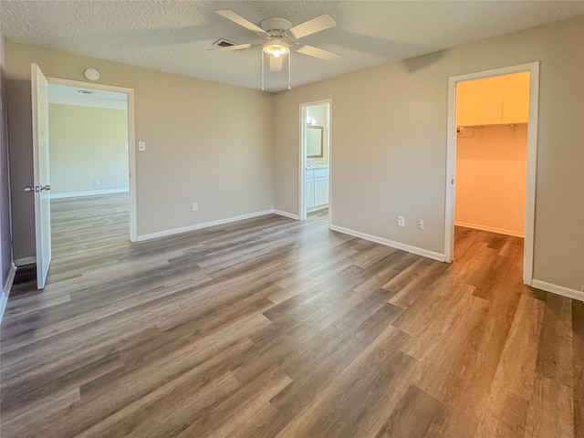 empty room with visible vents, a textured ceiling, baseboards, and wood finished floors